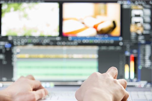 Hands of a man on his computer while editing a video.