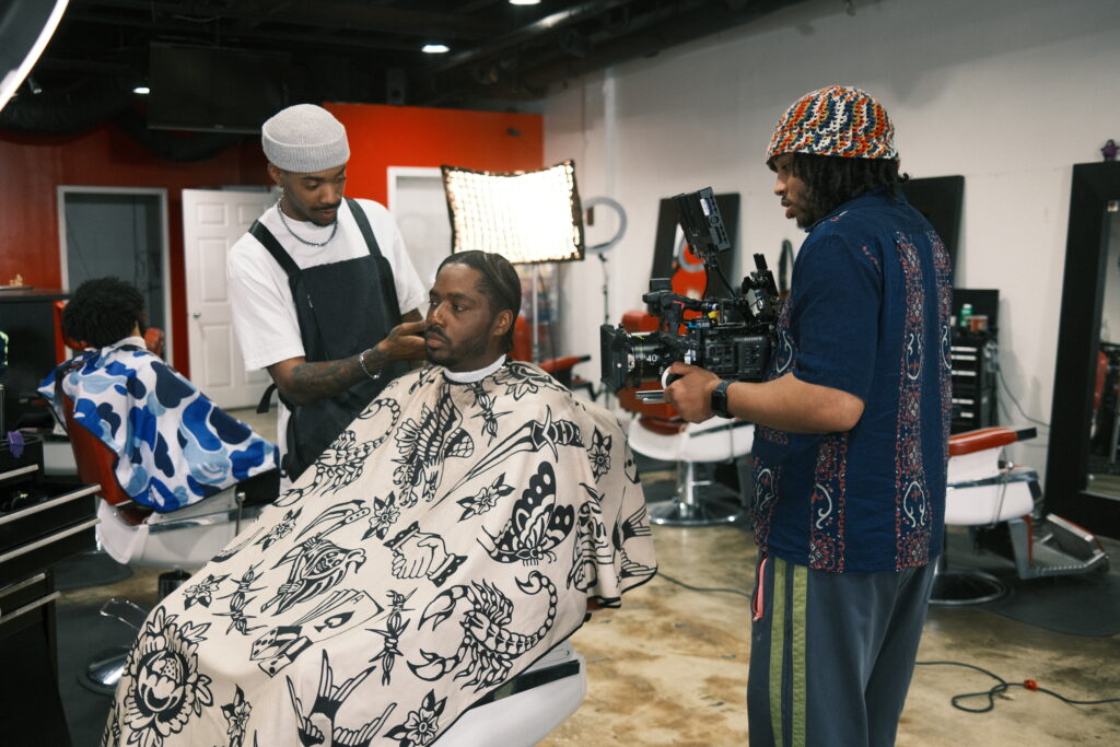 Image of Christian Nolan Jones filming a a man getting a shave from a barber for his Re: Stock collection.
