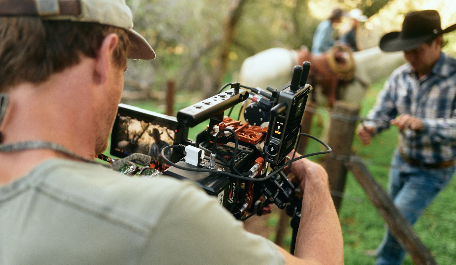 Image with an over the shoulder  shot of a Storyblocks Re: Stock contributor on set, filming cowhands at work for his footage collection.